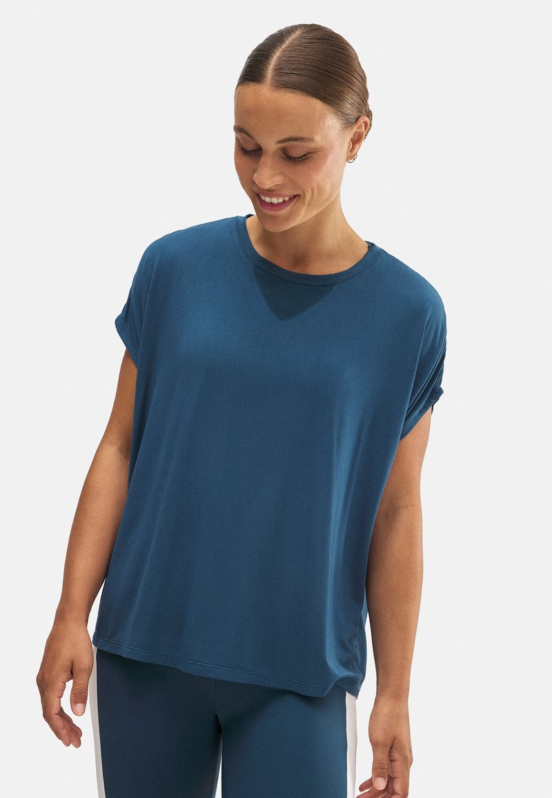 Camiseta de manga corta y corte holgado en azul profundo, con un escote redondo y un sutil acento triangular en el cuello. Tejido suave y liso.