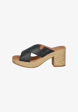 Sandalia deslizante de cuero negro con tiras cruzadas, plantilla color marrón claro y un tacón con estilo de cuerda trenzada. Cuenta con un pequeño acento rojo en la tira.