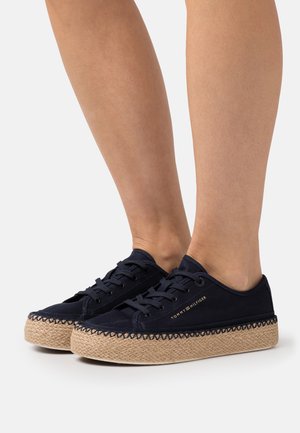 Zapatillas de lona azul marino con suela de yute trenzada, que presentan ojales de metal, cierre con cordones y costuras decorativas alrededor del borde de la suela.