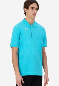 Polo shirt turchese in cotone, con colletto classico, maniche corte e un piccolo logo bianco sul lato sinistro del petto.