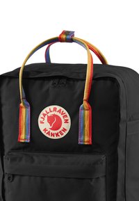Zaino di stoffa nero con manico color arcobaleno e una toppa rotonda con un siluetta di volpe rossa e il testo "Fjällräven Kånken".