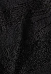 Tissu noir avec des couches texturées présentant des motifs complexes. Les sections comprennent des designs unis, côtelés et en dentelle pour un contraste visuel.