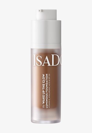 Flacon-pompe de fond de teint lumineux IsaDora Wake Up The Glow avec vitamine E, acide hyaluronique et SPF 50 présenté sur fond blanc.