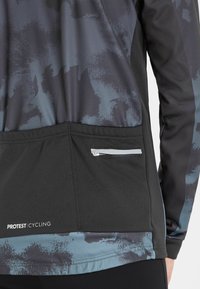 Protest fietsjack, kenmerkt zich door een donker, abstract patroon met een zwarte onderpan en een ritszak aan de achterkant voor opbergruimte.