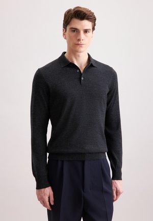 Dunkelgraues Langarm-Polo-Shirt aus einem weichen, strukturierten Stoff mit einer Knopfleiste mit drei Knöpfen und gerippten Bündchen, kombiniert mit marineblauen Hosen.
