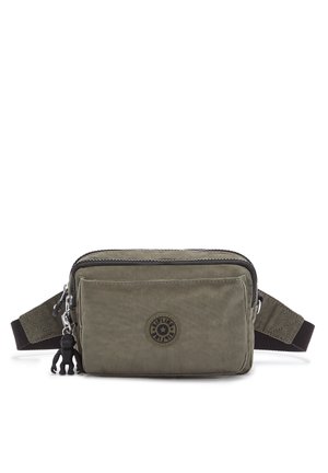 Olive green fabric shoulder bag with a zip closure, a smooth texture, a circular logo patch, and a black strap with a detachable charm.