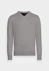 Pull à manches longues gris clair avec col en V, petit logo Tommy Hilfiger brodé sur la poitrine gauche.