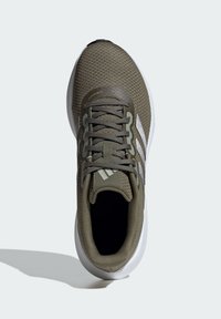 Zapatillas deportivas en verde oliva con parte superior de malla texturizada, con cordones grises y acentos blancos, sobre una suela blanca con punta redondeada.