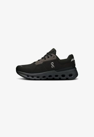 Black athletic shoes with a textured upper, featuring a gray accent, round laces, and a flexible sole with hexagonal cutouts.