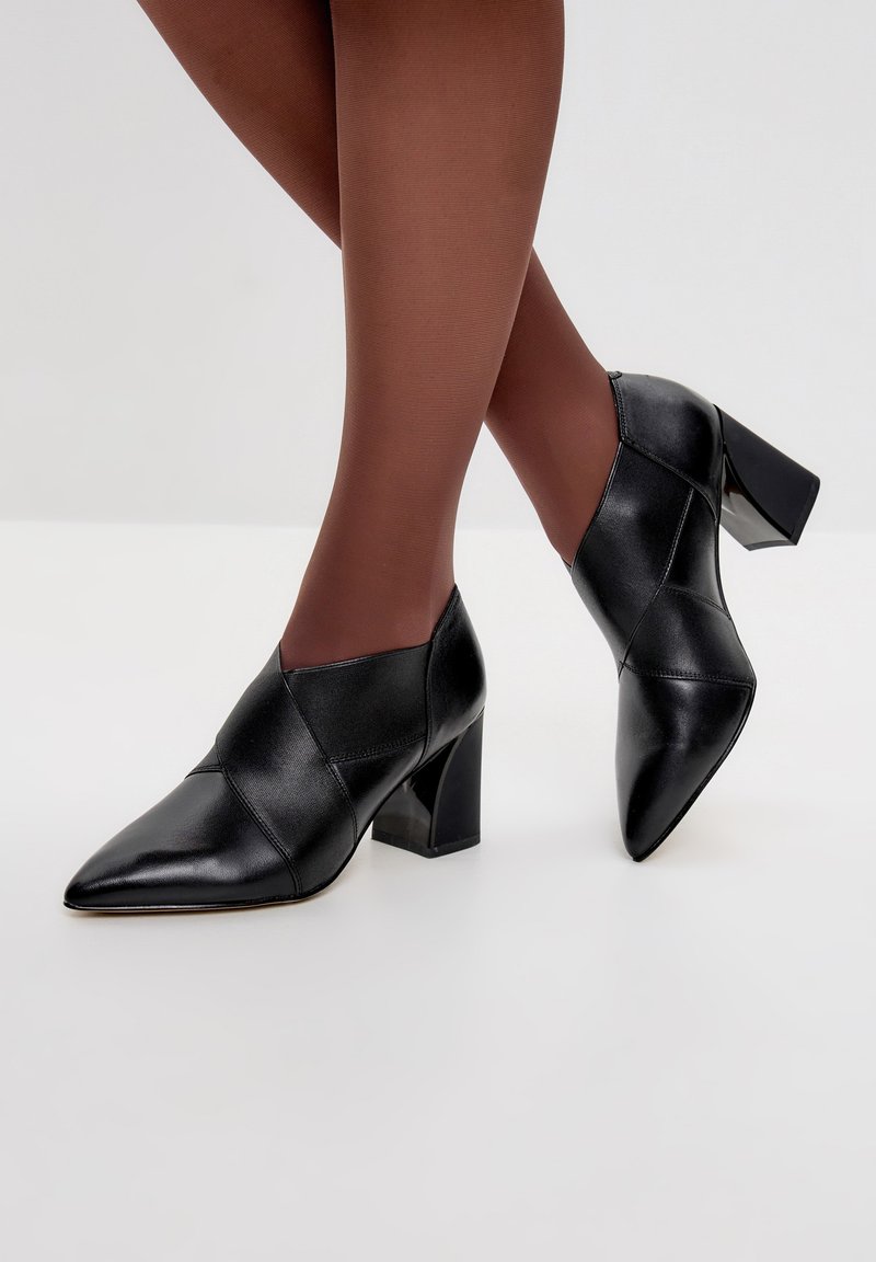 Scarpe nere in pelle con tacco alto, punta affilata e design angolare. I tacchi sono robusti, offrendo stabilità al calzature.