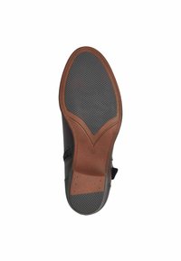 Suela de zapato negra con un diseño texturizado, de goma negra y un acento de cuero marrón. La talla 37 está marcada en la superficie plana.