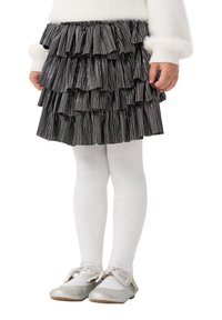 Gonna mini a balze a strisce nere e argento, con calze bianche e ballerine argento, decorate con un fiocco sulle scarpe.