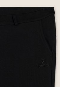 Pantalones deportivos negros con una textura suave, diseño sencillo, bolsillos laterales y un logo discreto de Freddy en la parte frontal inferior.