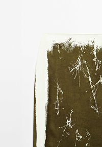 Jupe avec motif abstrait de coups de pinceau blancs sur tissu vert olive, présentant des bords irréguliers et une texture usée.