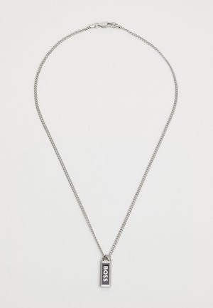 Sølvkjede med et rektangulært anheng som har ordet "BOSS" i fete hvite bokstaver mot en svart bakgrunn.