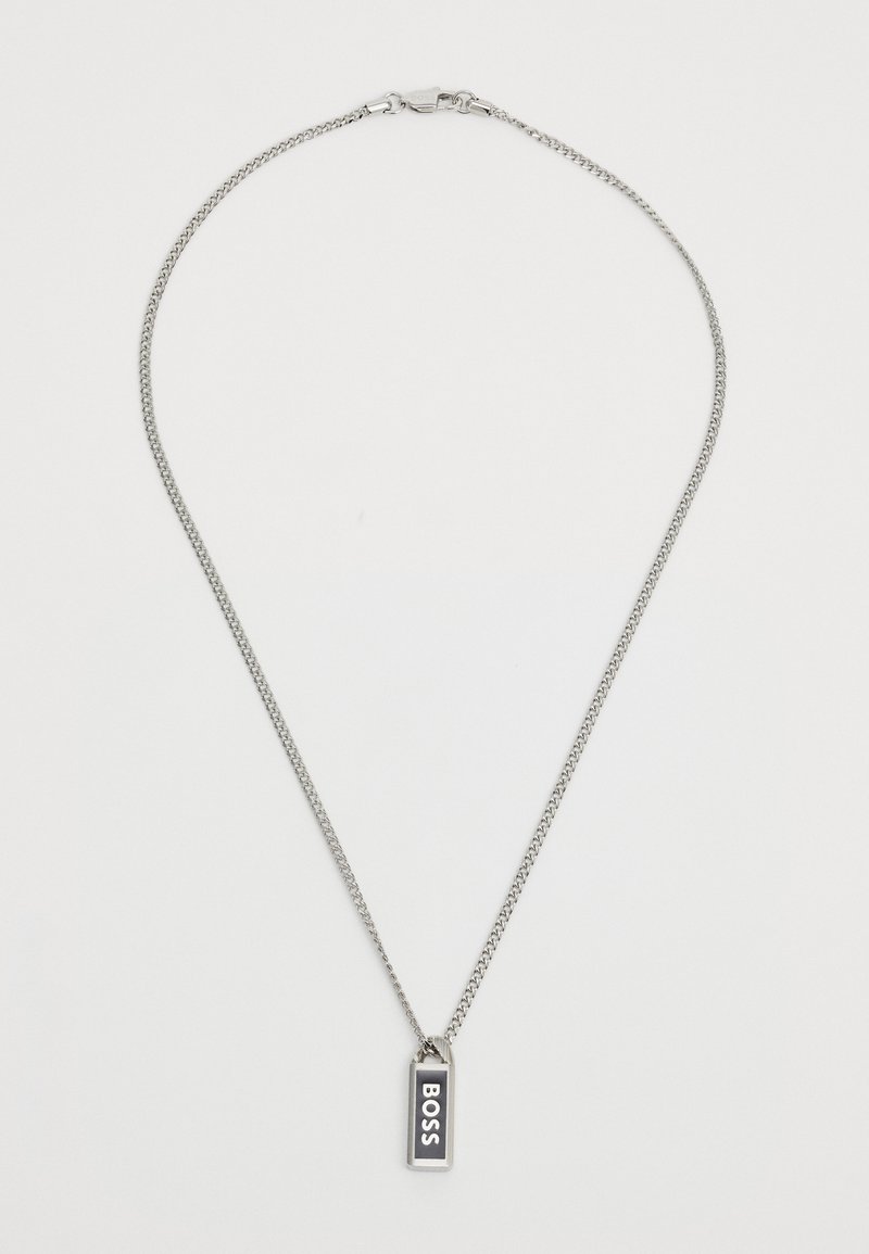 Collier en chaîne en argent avec un pendentif rectangulaire sur lequel est inscrit le mot "BOSS" en lettres blanches en gras sur fond noir.
