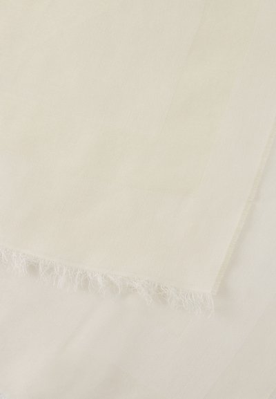Tissu doux beige clair avec un motif tissé discret et un bord à franges, étalé à plat en couches superposées.