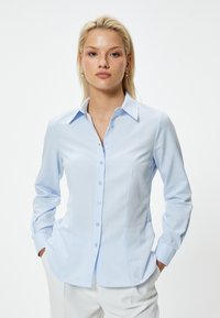 Lichtblauwe, lange mouwen button-up overhemd met een klassieke kraag, getailleerd ontwerp en subtiele textuur. Voorzien van knoopsluiting en gebogen zoom.