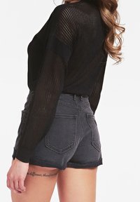 Zwarte lange mouwen top van mesh met geribbelde boorden, gecombineerd met high-waisted donkergrijze denim shorts met achterzakken en onafgewerkte randen.