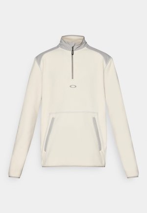 Cremefarbener Fleece-Pullover mit Halbreißverschluss-Kragen, grauen Schulterakzenten und seitlichen Taschen. Mit kleinem Logo auf der Brust.