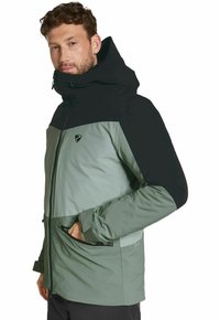 Grüne und schwarze isolierte Jacke mit Kapuze, mit einem Reißverschluss vorne, Seitentaschen und einem geometrischen Farbblock-Design.