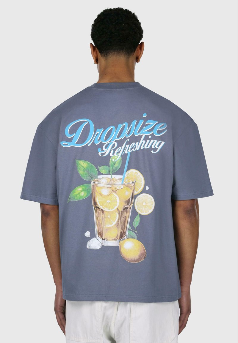 Grå T-shirt med korte ærmer, der prydes af et farverigt tryk af et glas lemonade med citroner, is og grønne blade på ryggen.