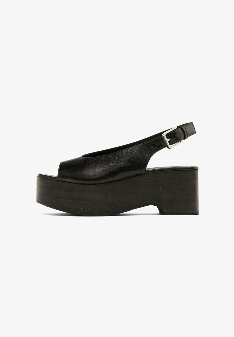 Black leather platform slingback shoes with a rounded toe, wide strap, and adjustable silver buckle. Textured sole, modern design.