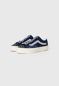 Mørkeblå og svarte mønstrede sneakers med hvite detaljer, flate lisser og gummisåle; teksturert overflate med mesh-detaljer.