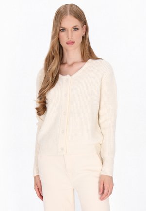 Cardigan de culoare crem, realizat dintr-un material tricotat moale și texturat. Are un decolteu în V, manșete strânse și închidere cu nasturi în față. Croială lejeră.