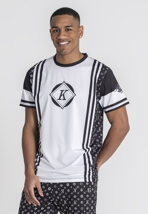 Camisa atlética blanca y negra con diseños geométricos, que presenta un logo central y acentos a rayas. Tejido suave con un corte relajado.