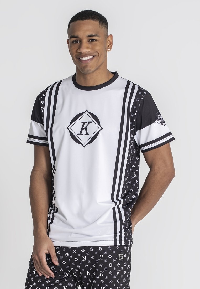 Camisa atlética blanca y negra con diseños geométricos, que presenta un logo central y acentos a rayas. Tejido suave con un corte relajado.