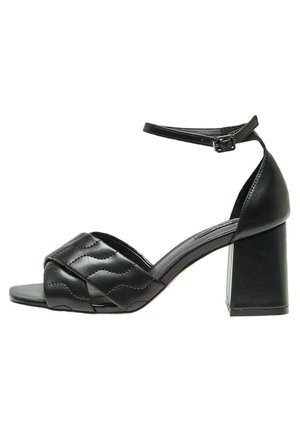 Czarne skórzane sandały na obcasie z szerokim paskiem ozdobionym falistym przeszyciem, odkrytymi palcami i blokowym obcasem, zapinane na regulowany pasek wokół kostki.