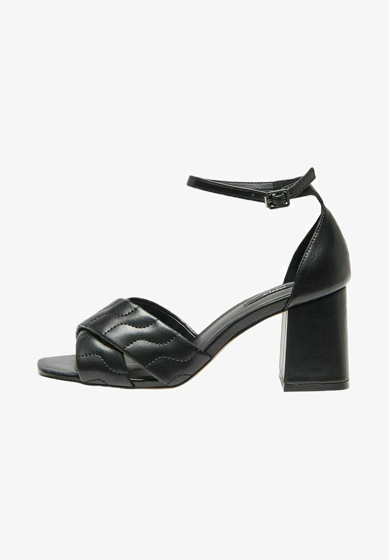 Sandales à talons en cuir noir avec une large bride ornée d’un détail de couture ondulée, bout ouvert, talon bloc, maintenues par une bride de cheville réglable.