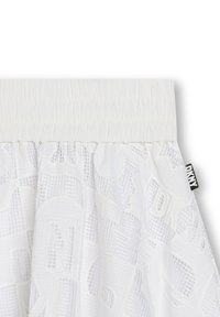 Jupe blanche évasée en tissu texturé avec un overlay à motifs. Comprend une petite étiquette noire DKNY au niveau de la taille.