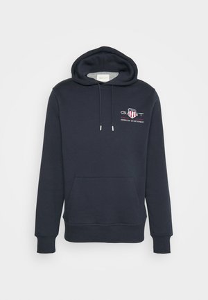 Hoodie bleu marine en tissu doux, doté d'une poche kangourou à l'avant, d'une capuche avec cordon de serrage et d'un logo brodé sur la poitrine.