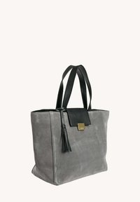 Sac fourre-tout en daim gris avec des accents en cuir noir, forme rectangulaire, deux poignées noires, et un logo carré doré près du rabat supérieur.