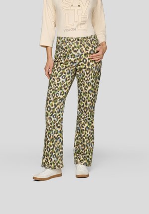 Leopardenmuster-Hosens in grünen und beigen Tönen, mit einem geraden Bein-Design. Kombiniert mit weißen Sneakers und einem hellen Cremeoberteil.