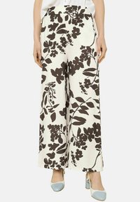 Pantaloni a gamba larga in tessuto bianco con grandi motivi floreali marroni, vita piatta e vestibilità rilassata. Abbinati a tacchi bicolore.