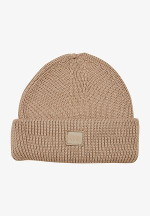 Beżowa dziana czapka beanie z podwiniętym brzegiem i kwadratową metką. Teksturowany, miękki materiał z prążkowanym wzorem.