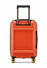 Maleta de concha dura de color naranja brillante con mango telescópico y cuatro ruedas amarillas, mostrada de pie desde la parte de atrás.