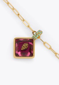 Collana con catena dorata che presenta un ciondolo quadrato in gemma rosa con un accento dorato texturizzato e una fascia di cristalli verdi scintillanti.