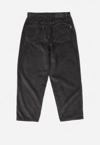 Pantaloni in corda nera con vestibilità rilassata, dotati di due tasche posteriori e una superficie testurizzata. Vita elasticizzata con un'etichetta nera sul retro.