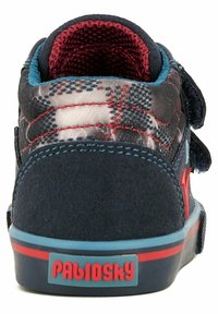 Zapatilla infantil de color azul marino con acentos en rojo y tejido de cuadros, cierre con cinta de Velcro, cuello acolchado y logotipo en la parte trasera.
