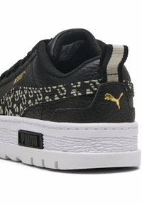 Czarny sneaker z teksturowanej skóry, białą podeszwą i złotymi akcentami. Posiada leopardzi wzór wzdłuż boku oraz paskowy uchwyt.