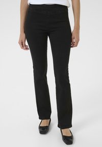Schwarze Jeanshose mit geradem Beinansatz, ausgestattet mit einem glatten Bund und dezenten Nähdetails, kombiniert mit schwarzen flachen Schuhen.