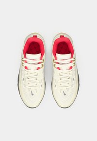 Hvide mesh sneakers med rød indre foring, gyldne øjer og sort sål. Har en tekstureret overdel og kontrasterende snørebånd.