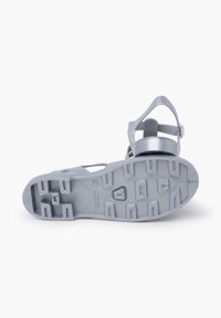 Gray plastic sandal with a textured sole, an adjustable ankle strap, and a ventilated design for breathability.