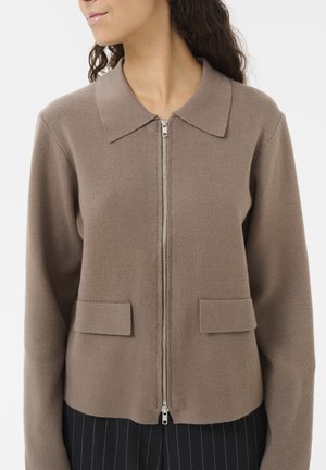 Veste zippée marron avec un col structuré, dotée de deux poches avant. Le tissu a une texture lisse et une coupe ajustée.