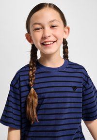 Navyblauw T-shirt met korte mouwen, voorzien van zwarte, brede horizontale strepen en een klein zwart logo op de borst. Gemaakt van katoen, met een ontspannen pasvorm.