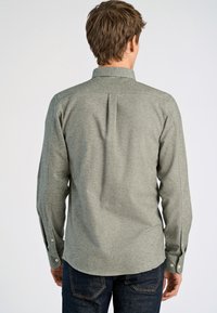 Grijs shirt met lange mouwen van textuurstof, met een button-down kraag, een rugplooi en knoopmanchetten. Gecombineerd met donkere jeans.